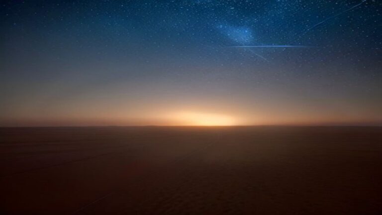Glow on a dark horizon beneath a starry night sky