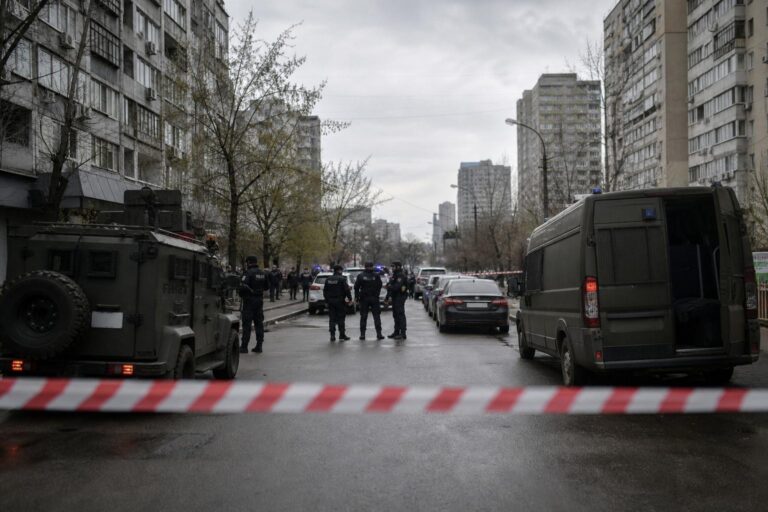 Police and armored vehicles behind red-and-white tape on a city street