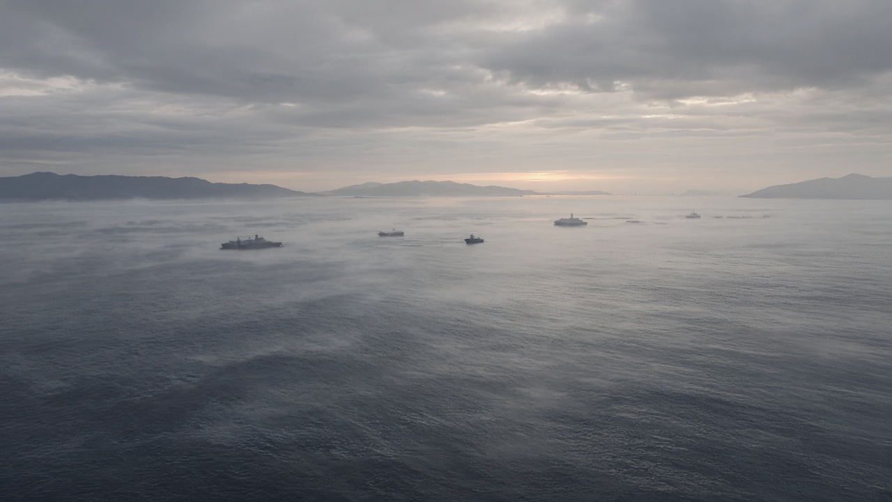 Several grey warships spread across a calm sea under low cloud