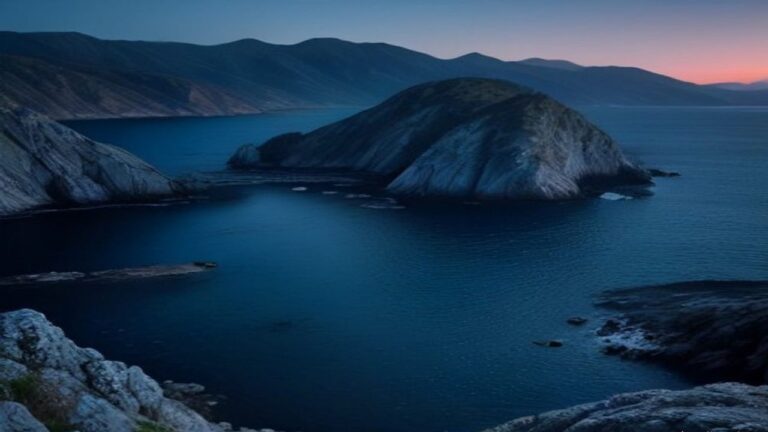 Rocky coastal inlets and a headland in deep blue water at twilight