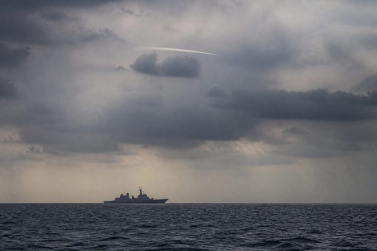 Lone warship on a grey sea beneath heavy storm clouds