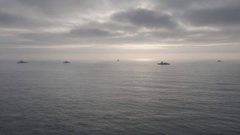 Overcast grey sea with a line of distant warships along the horizon