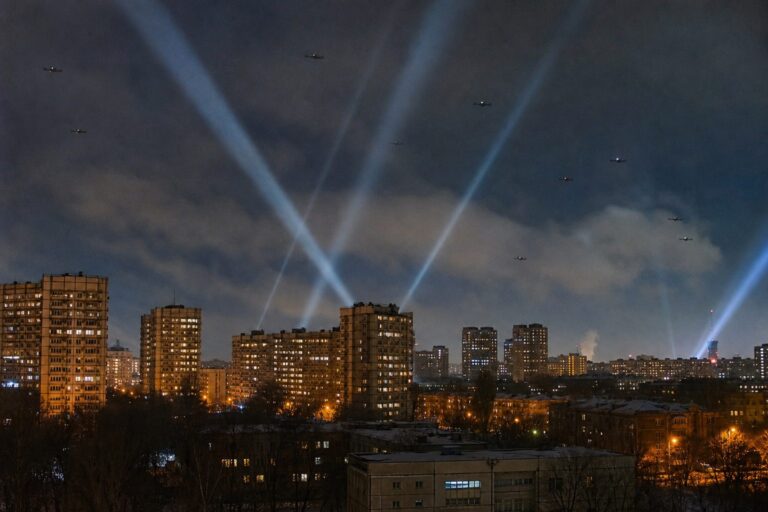Searchlight beams sweeping the night sky over lit apartment towers