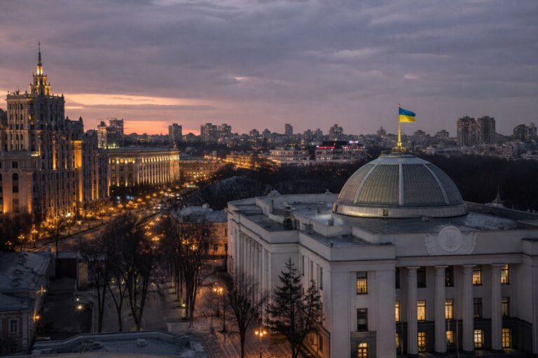 Domed parliament building flying a Ukrainian flag in a city at dusk