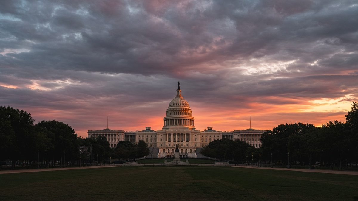 White dome of the US Capitol lit by golden sunset light under dark clouds and an orange and purple sky